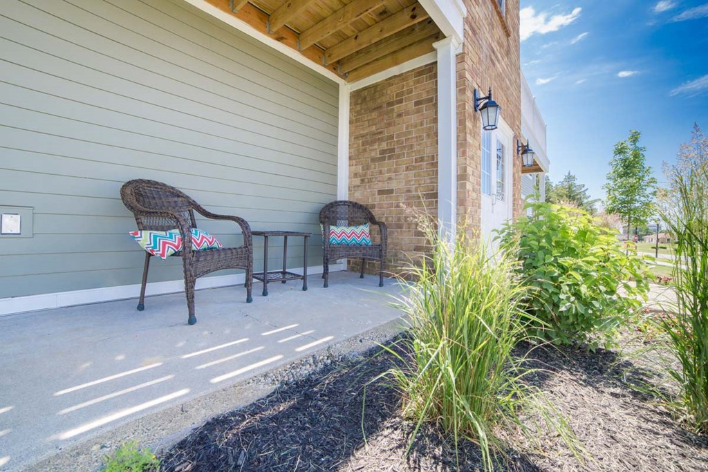 two wicker chairs on a porch in front of a house