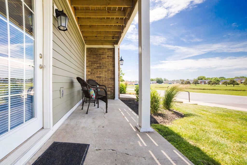 a covered porch with a chair and a view of the field