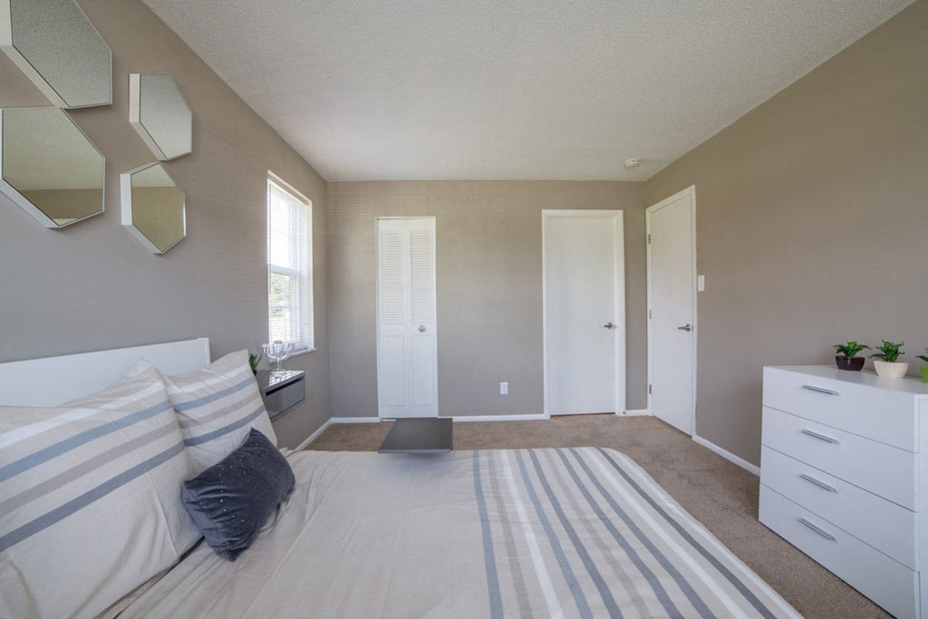 a bedroom with a bed and a dresser and a window