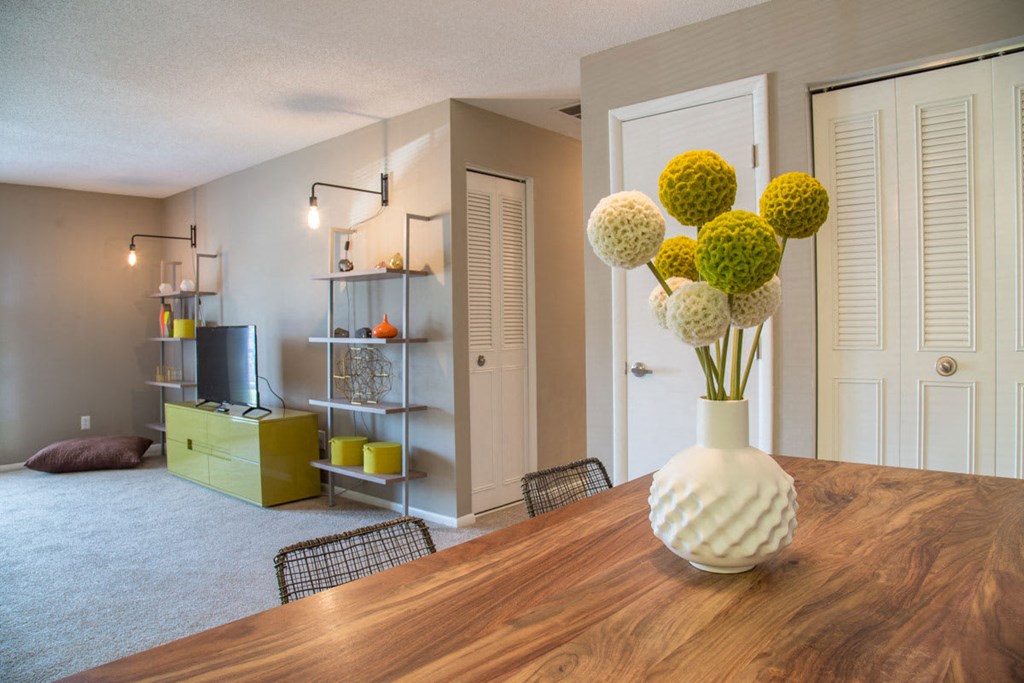 a dining room with a wooden table and a vase of flowers