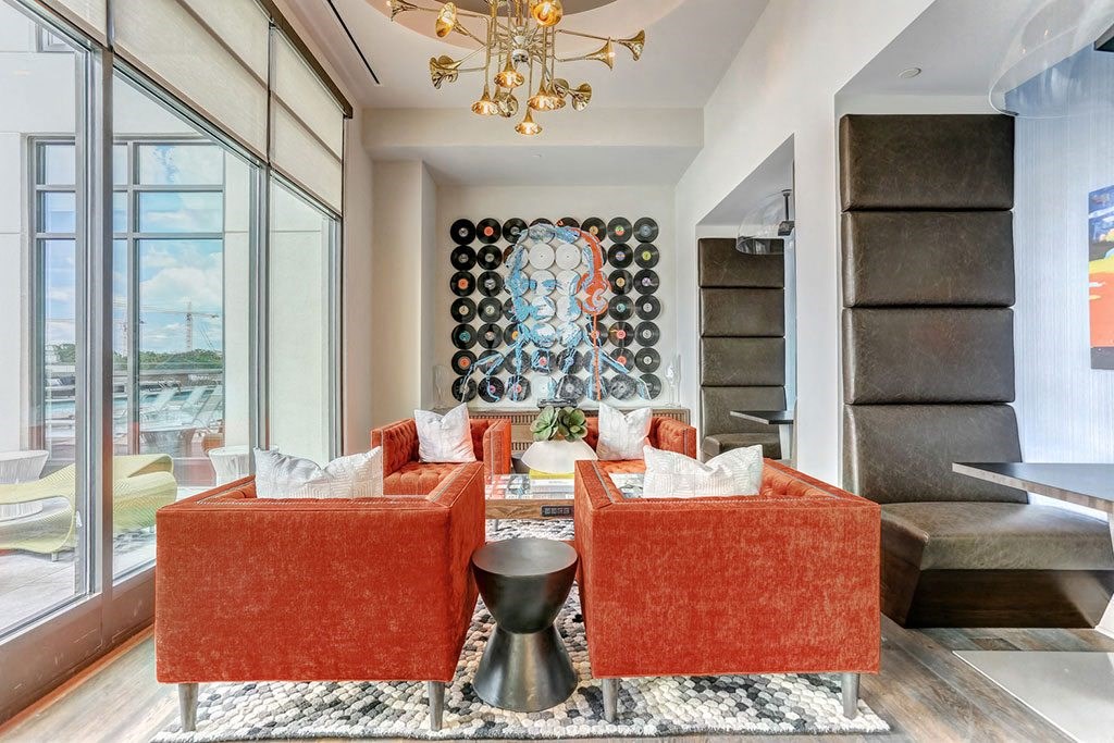 a living room with orange couches and a large painting on the wall