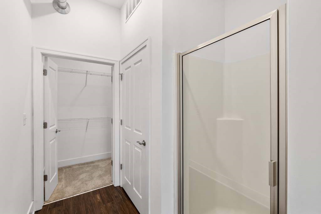 A white bathroom with a walk in shower and a glass door.at The Foundry, Indiana