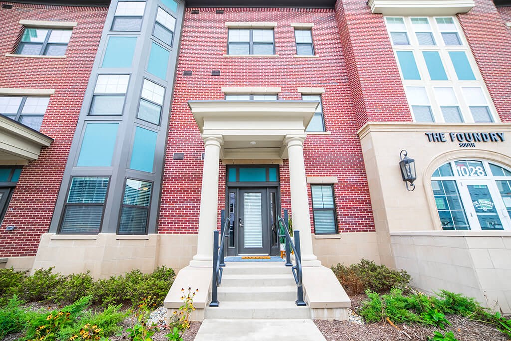 a red brick building with a glass door and steps in front of it at The Foundry, South Bend Indiana