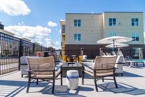 a patio with tables and chairs and a building in the background at The Century at Purdue Research Park-Student, West Lafayette, IN