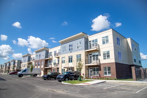 an apartment building with cars parked in a parking lot at The Century at Purdue Research Park-Student, West Lafayette