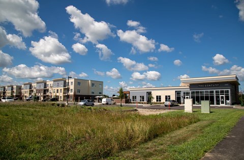 a row of apartment buildings with a field in front of them at The Century at Purdue Research Park-Student, Indiana, 47906