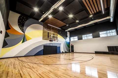 a basketball court in a gym with a colorful wall and wood floors at The Century at Purdue Research Park-Student, West Lafayette