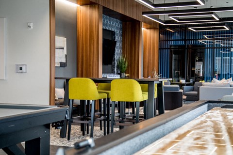 a bar with yellow chairs and tables in a lobby at The Century at Purdue Research Park-Student, West Lafayette, IN
