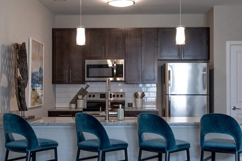 a kitchen with four blue chairs in front of a counter topat The Century at Purdue Research Park-Student, West Lafayette, IN 47906