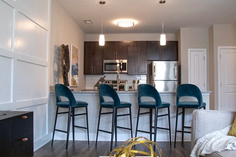 a kitchen with bar stools and a kitchen island with stools at The Century at Purdue Research Park-Student, West Lafayette Indiana