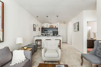 a living room with a couch and a chair and a kitchen at 310 at Nulu Apartments-Student, Louisville Kentucky