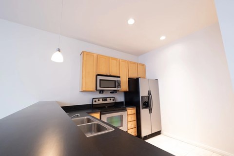 A modern kitchen with wooden cabinets and a black countertop.