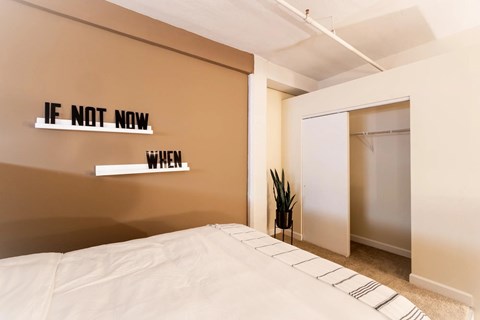 Bedroom with motivational wall decor and open closet at Indy Living Apartments, Indianapolis, Indiana