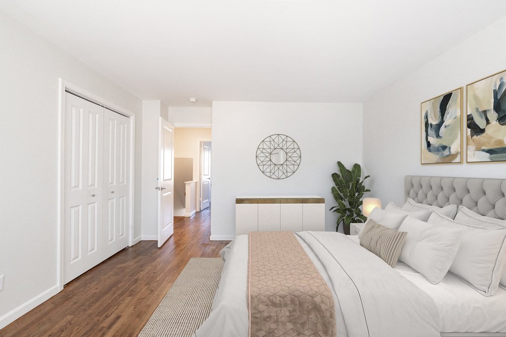 a bedroom with white walls and hardwood floors