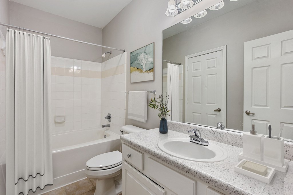 A white bathroom with a toilet, sink, and shower.