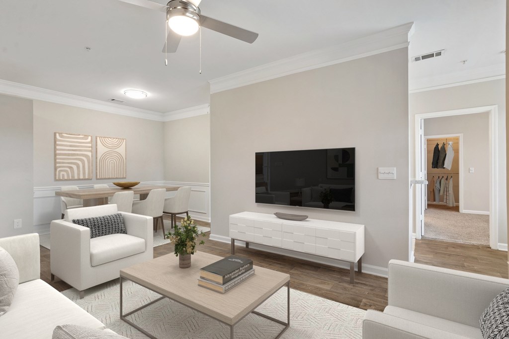 A living room with a white couch, a coffee table, and a television.
