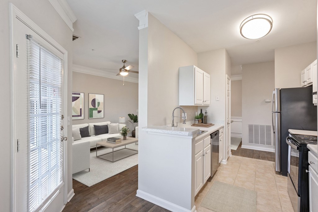 A kitchen with white cabinets and a black refrigerator.