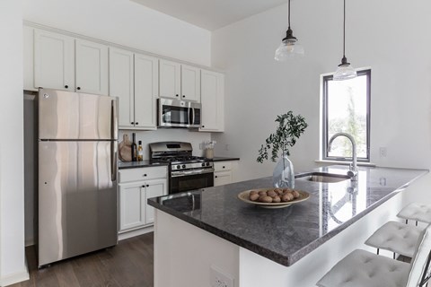 a kitchen with white cabinets and stainless steel appliances and a marble counter top