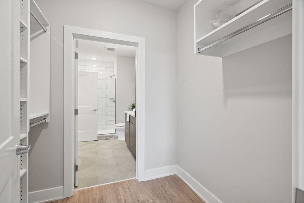 a white hallway with a door to a bathroom and a closet