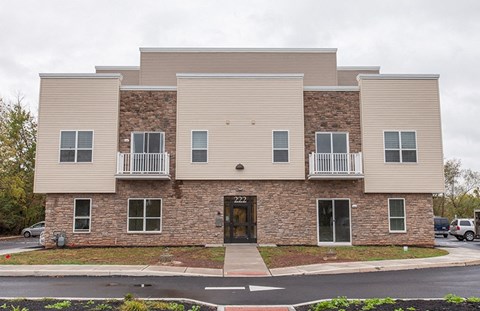 the front of a brick apartment building with a sidewalk