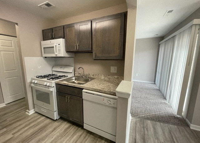 A kitchen with a white stove top oven and a white microwave above it.