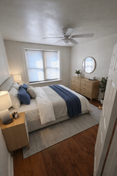 A bedroom with a bed, nightstand, and window.