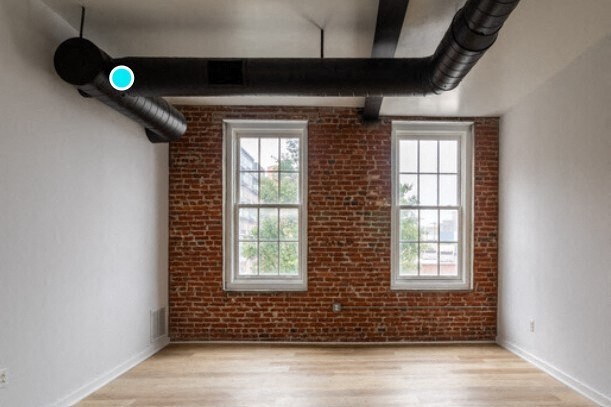 an empty room with a red brick wall and two windows