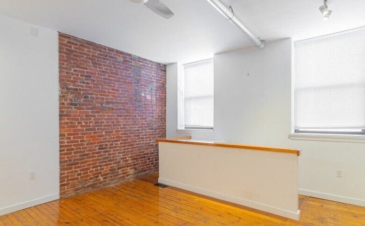 an empty room with a brick wall and a desk