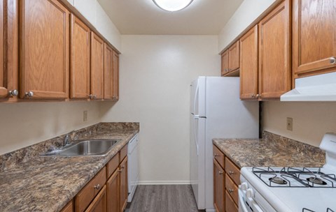 A kitchen with brown cabinets and a white refrigerator.