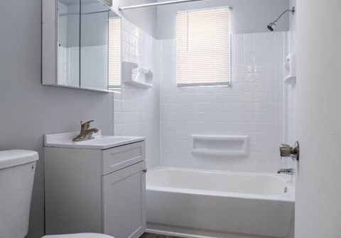 A white bathroom with a toilet, sink, and bathtub.