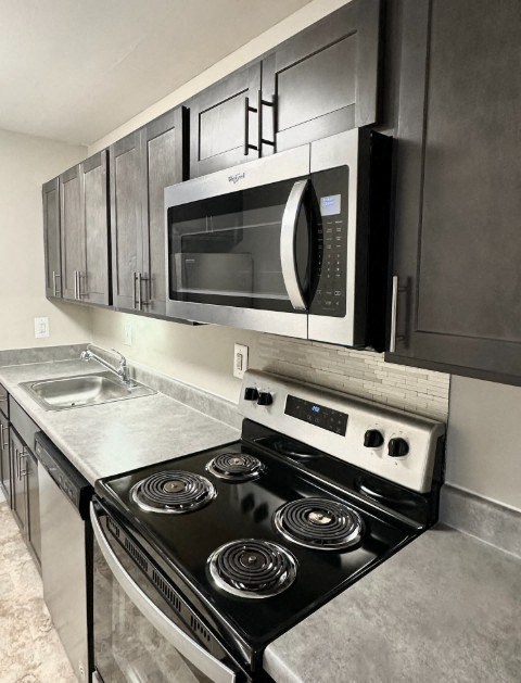A black and silver kitchen with a stove and microwave.