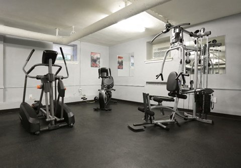 A gym with a treadmill, a stationary bike, and a weight machine.