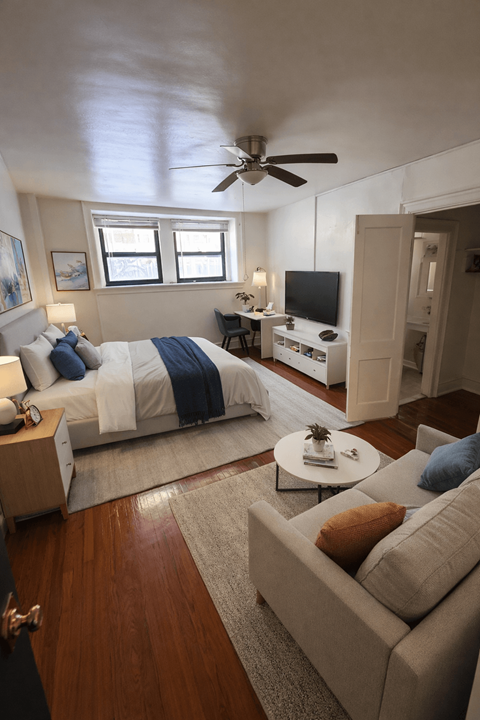 A bedroom with a bed, a couch, and a ceiling fan.