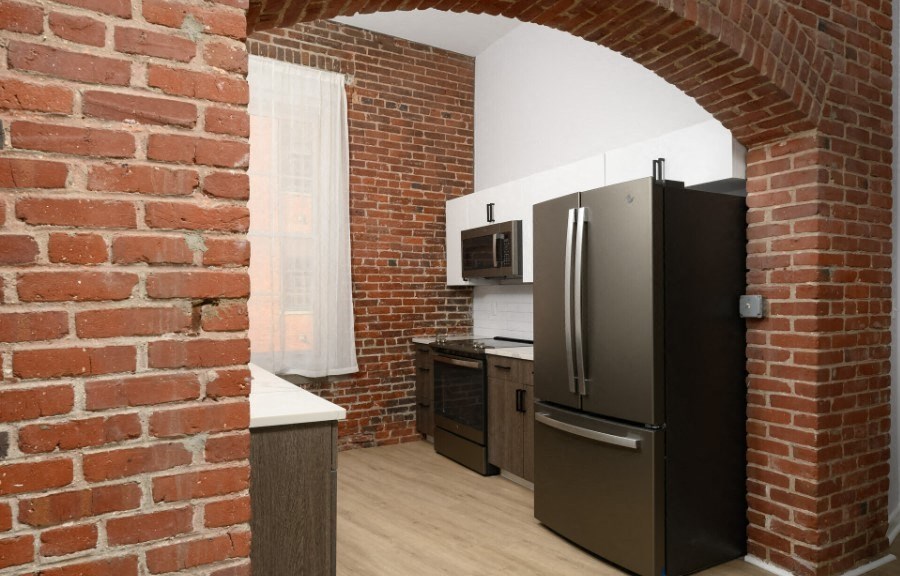 a kitchen with a brick wall and a black refrigerator