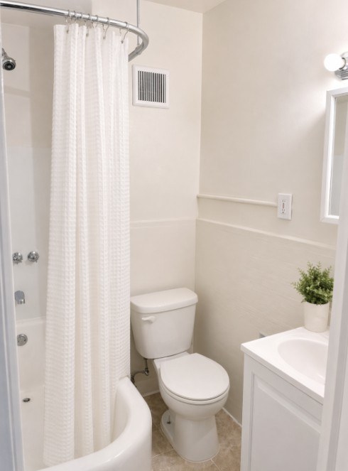 A white bathroom with a toilet, sink, and shower.