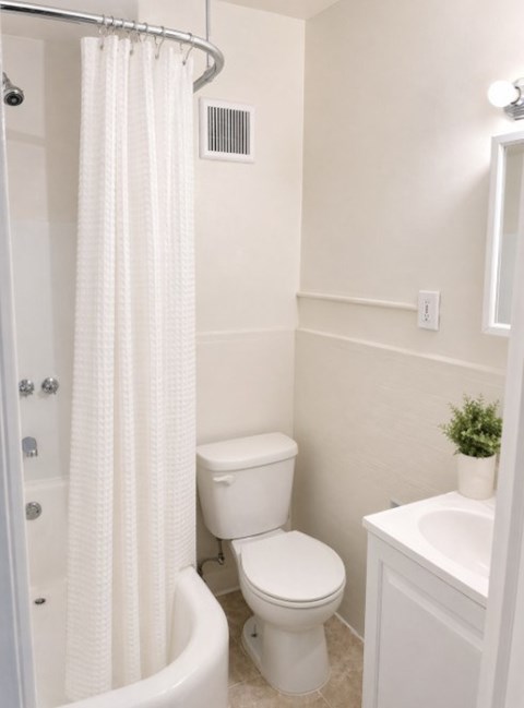 A white bathroom with a toilet, sink, and shower.