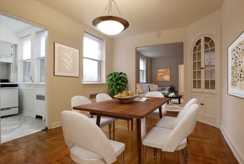 A dining room with a wooden table and white chairs.