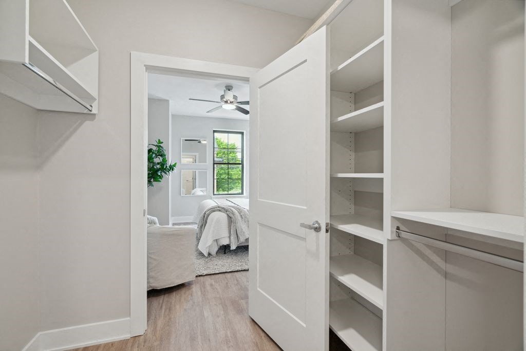 a white closet with a door open to a bedroom