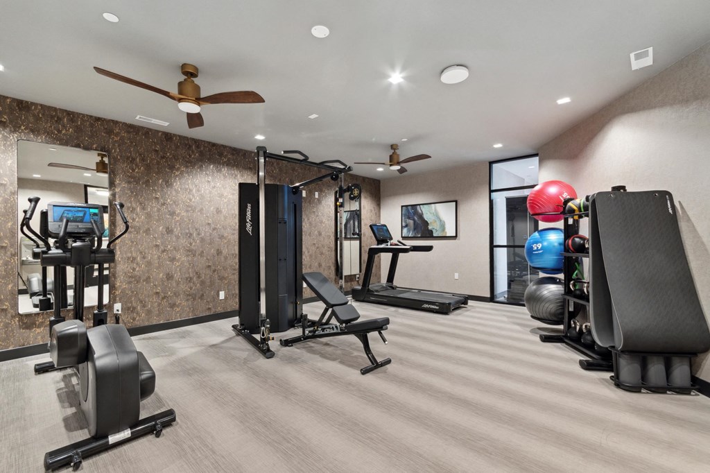 a home gym with exercise equipment and a ceiling fan