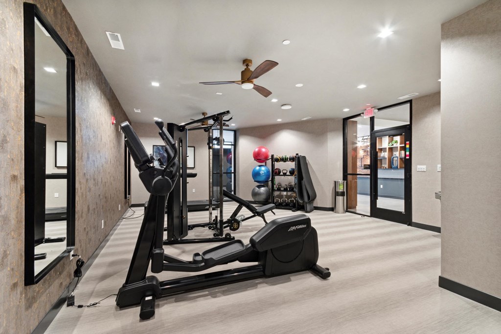 a gym with exercise equipment and a ceiling fan