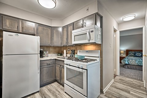 A kitchen with a white refrigerator, stove, and microwave.