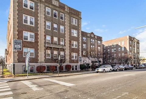 A street view of a residential area with apartment buildings and parked cars.