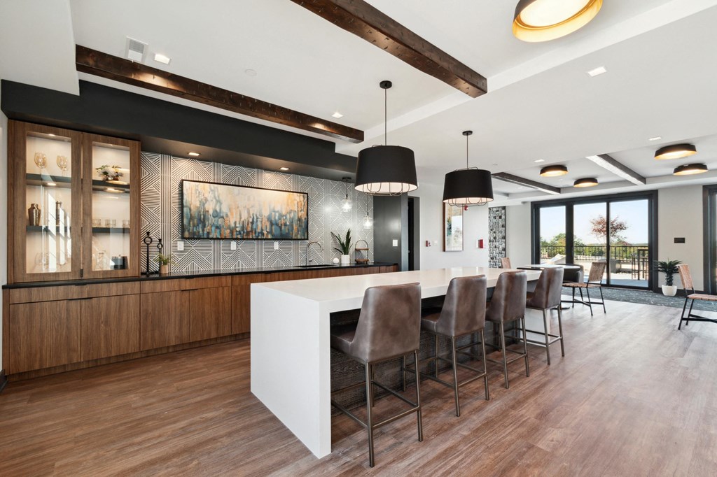 a kitchen with a long white counter and chairs