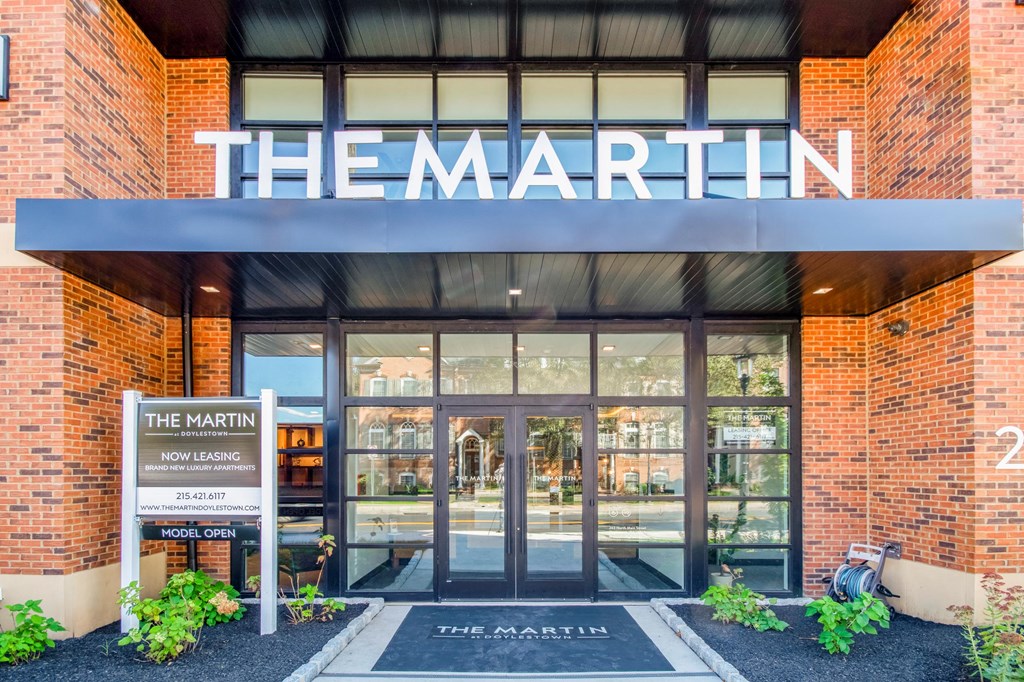 the front of the building with glass doors and a sign