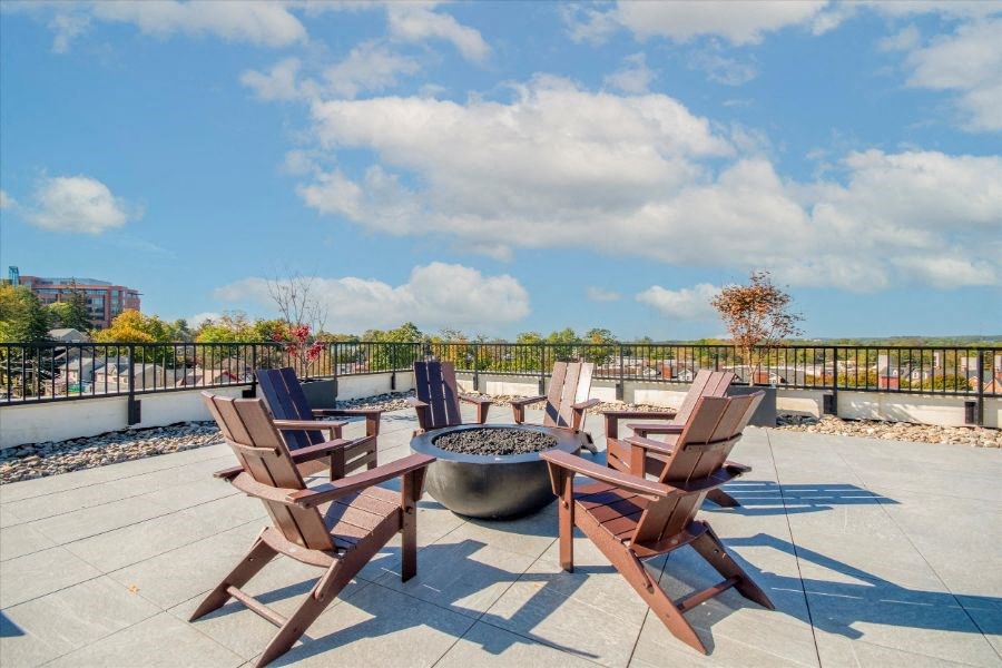a patio with wooden chairs and a fire pit