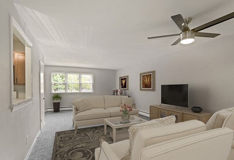 A living room with a couch, a television, and a ceiling fan.