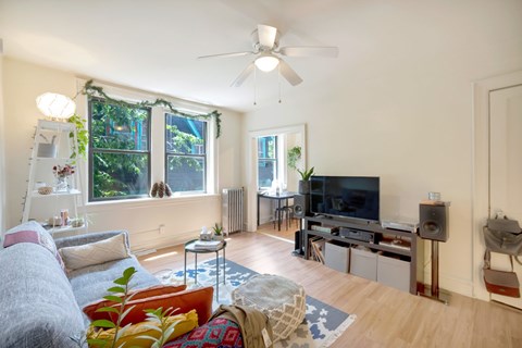 A living room with a grey couch and a white ceiling fan.