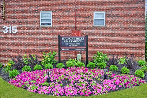 A sign for Hickory Hills Apartments is in front of a brick building.