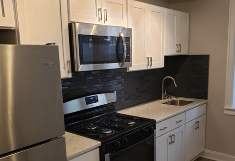 A kitchen with a stove, refrigerator, and microwave.