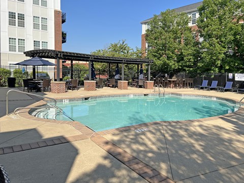 A large outdoor pool with a patio and umbrellas.
